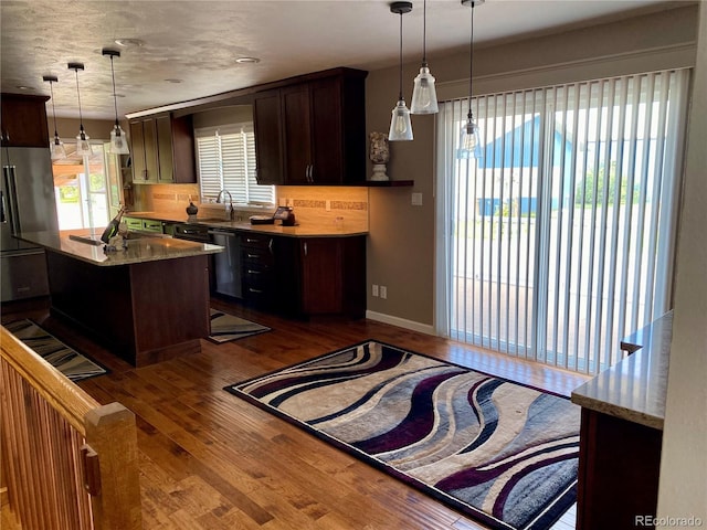 kitchen with backsplash, dark brown cabinetry, sink, pendant lighting, and wood-type flooring