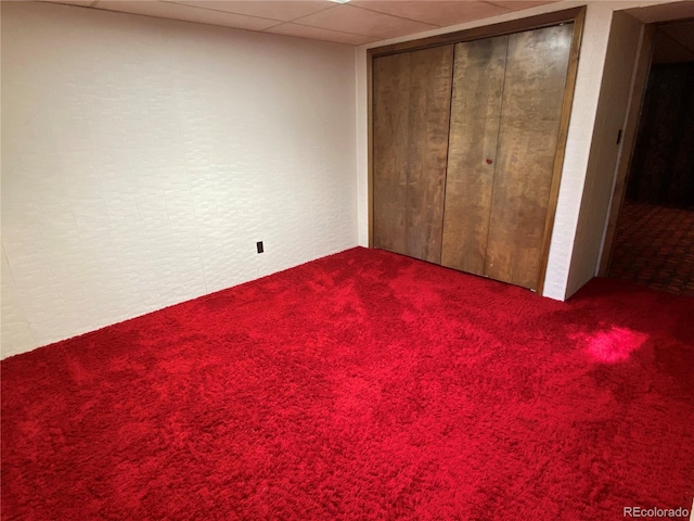 unfurnished bedroom with carpet flooring, a closet, and a drop ceiling