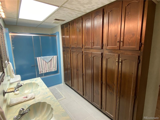 bathroom with tile patterned floors, double vanity, and a drop ceiling