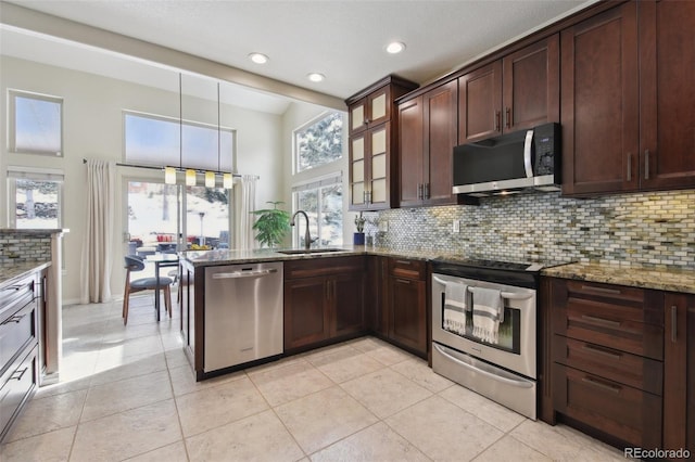 kitchen featuring sink, backsplash, hanging light fixtures, stainless steel appliances, and light stone counters