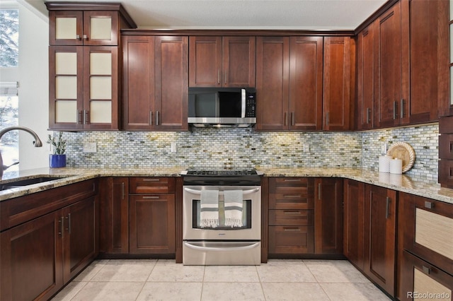 kitchen with stainless steel appliances, tasteful backsplash, sink, and light stone counters