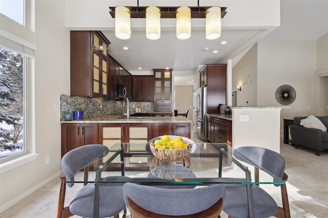 kitchen with light stone counters, hanging light fixtures, tasteful backsplash, and stainless steel appliances