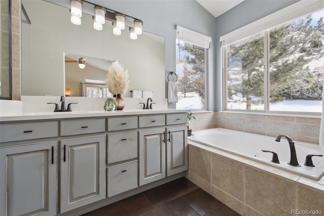 bathroom with lofted ceiling, vanity, tiled bath, and tile patterned flooring