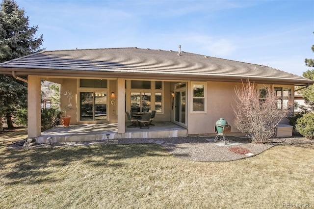 rear view of house with a patio and a lawn