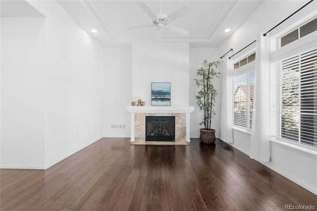 unfurnished living room featuring hardwood / wood-style floors, a raised ceiling, visible vents, and a tile fireplace