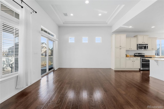 unfurnished dining area with visible vents, dark wood-type flooring, a tray ceiling, recessed lighting, and baseboards