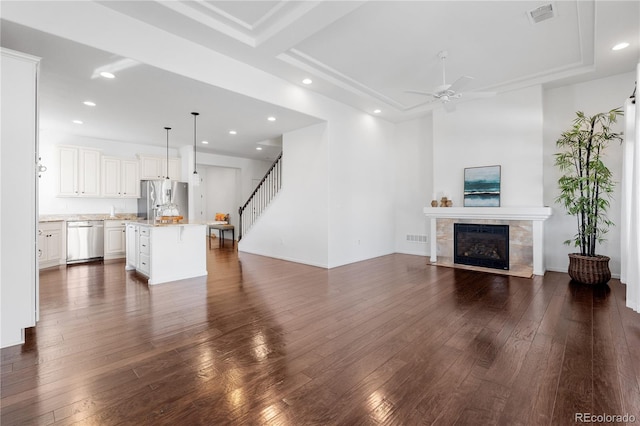unfurnished living room with visible vents, stairway, dark wood-style floors, and a tile fireplace