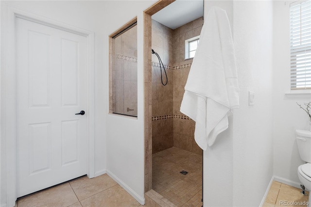 full bathroom featuring tile patterned floors, toilet, baseboards, and a tile shower