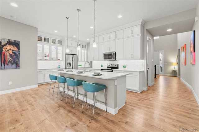 17720 W 94th Dr, Arvada, CO 80007 - kitchen with appliances with stainless steel finishes, a kitchen bar, tasteful backsplash, an island with sink, and light wood-style flooring
