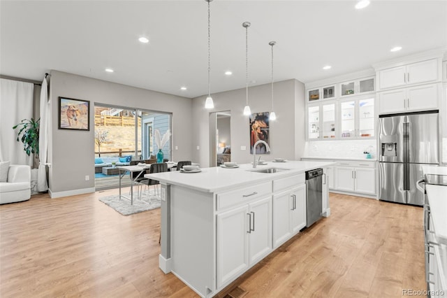 17720 W 94th Dr, Arvada, CO 80007 - kitchen with appliances with stainless steel finishes, a sink, light wood-style flooring, a kitchen island with sink, and light countertops
