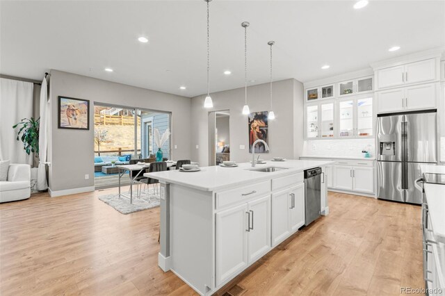17720 W 94th Dr, Arvada, CO 80007 - kitchen with stainless steel appliances, a sink, light wood-style floors, an island with sink, and light countertops