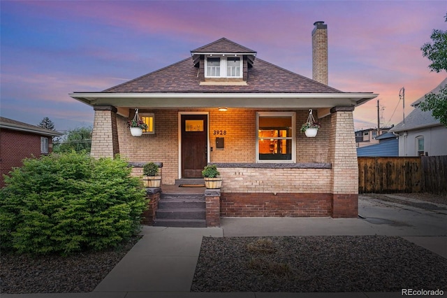3928 Zuni St, Denver, CO 80211 - bungalow featuring brick siding, a porch, fence, a chimney, and roof with shingles