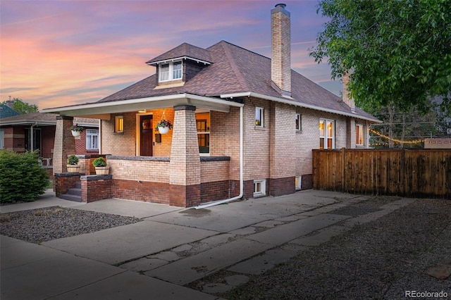 3928 Zuni St, Denver, CO 80211 - view of front of home featuring a chimney, fence, brick siding, covered porch, and a shingled roof