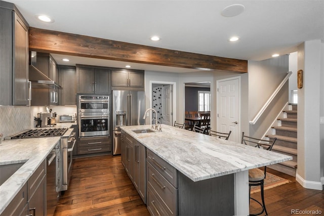 kitchen with a sink, dark wood-style floors, a breakfast bar area, beamed ceiling, and recessed lighting