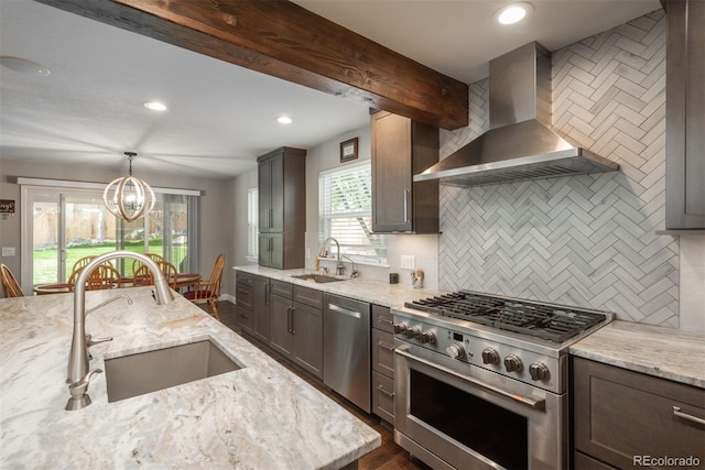 kitchen with appliances with stainless steel finishes, a sink, wall chimney range hood, tasteful backsplash, and recessed lighting
