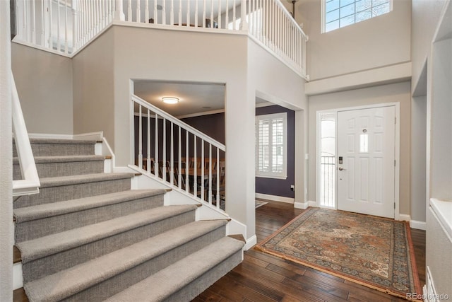 foyer entrance with stairs, a high ceiling, hardwood / wood-style flooring, and baseboards