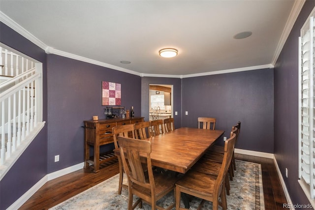 dining room featuring wood-type flooring, crown molding, and baseboards
