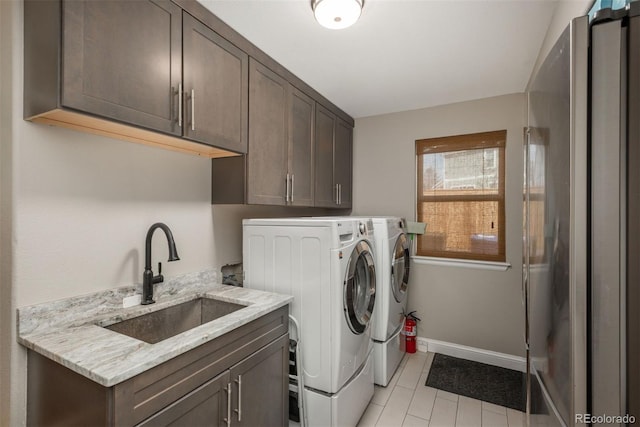 clothes washing area featuring washing machine and clothes dryer, cabinet space, light tile patterned floors, and baseboards