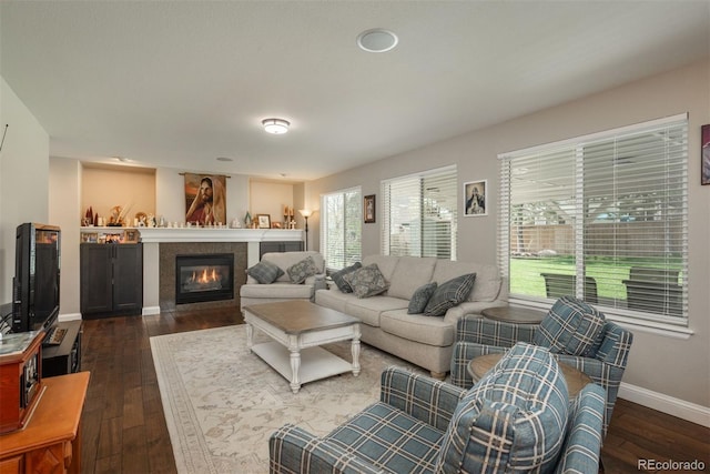 living room featuring dark wood-style flooring, baseboards, and a glass covered fireplace