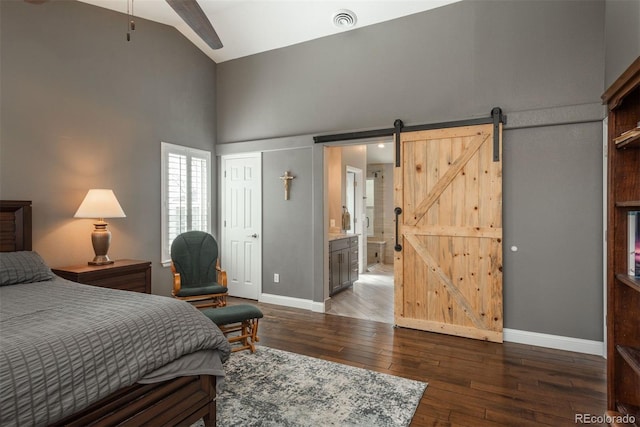 bedroom featuring high vaulted ceiling, baseboards, wood-type flooring, a barn door, and ensuite bath