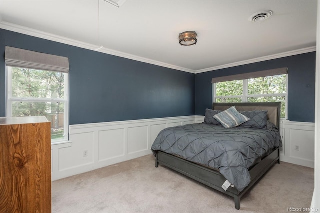 carpeted bedroom with a wainscoted wall, a decorative wall, and crown molding