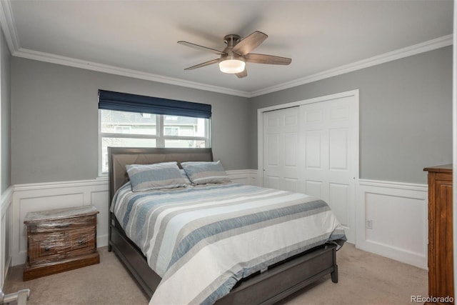 bedroom with a closet, carpet flooring, crown molding, a wainscoted wall, and a decorative wall