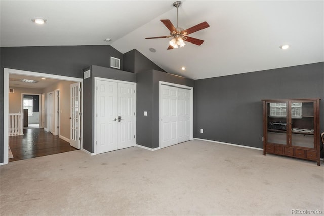 unfurnished bedroom with carpet flooring, multiple closets, high vaulted ceiling, baseboards, and a ceiling fan