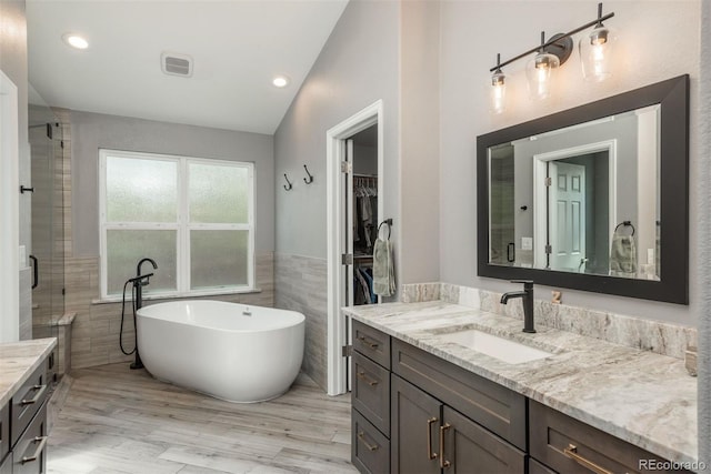 9325 Lark Sparrow Dr, Highlands Ranch, CO 80126 - bathroom featuring tile walls, lofted ceiling, vanity, a freestanding tub, and a stall shower