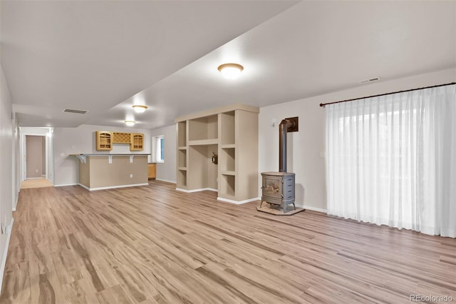 12454 Tex Tan Rd, Peyton, CO 80831 - unfurnished living room with a wood stove, light wood finished floors, and baseboards