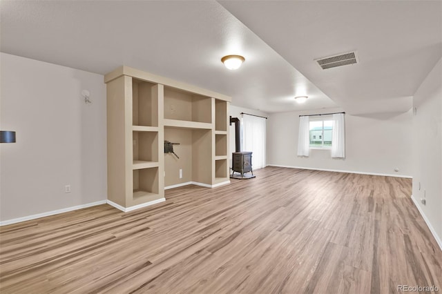 12454 Tex Tan Rd, Peyton, CO 80831 - unfurnished living room featuring a wood stove, light wood-type flooring, baseboards, and built in features