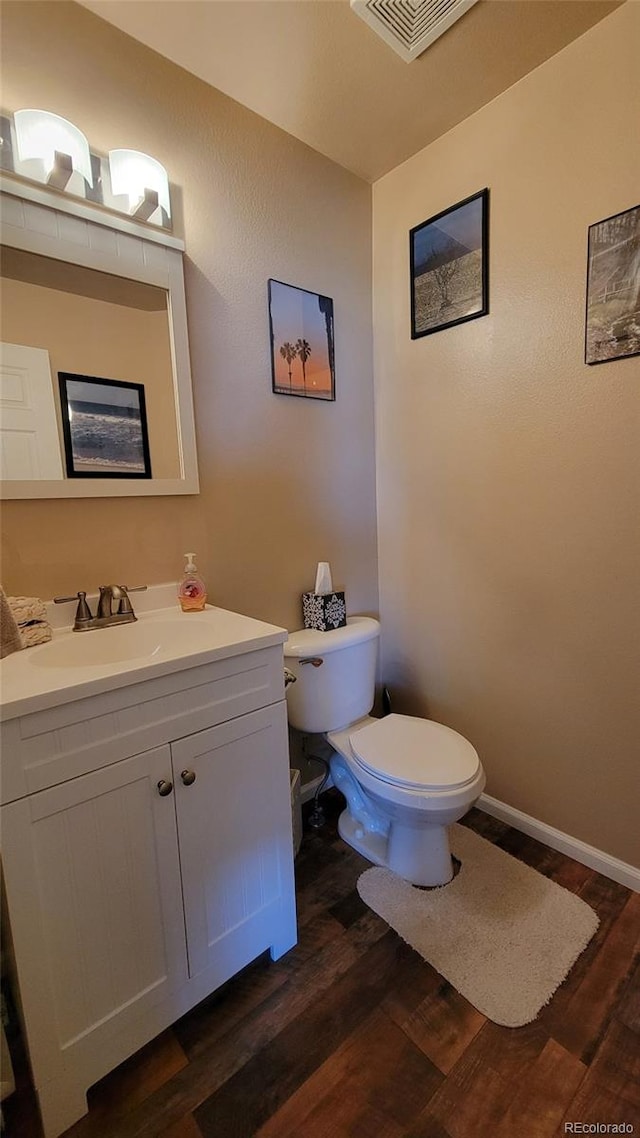 4214 Widener St, Pueblo, CO 81008 - half bathroom featuring wood finished floors, toilet, vanity, and baseboards