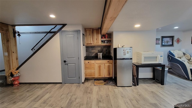 4214 Widener St, Pueblo, CO 81008 - kitchen featuring freestanding refrigerator, white microwave, light wood-style floors, dark countertops, and backsplash
