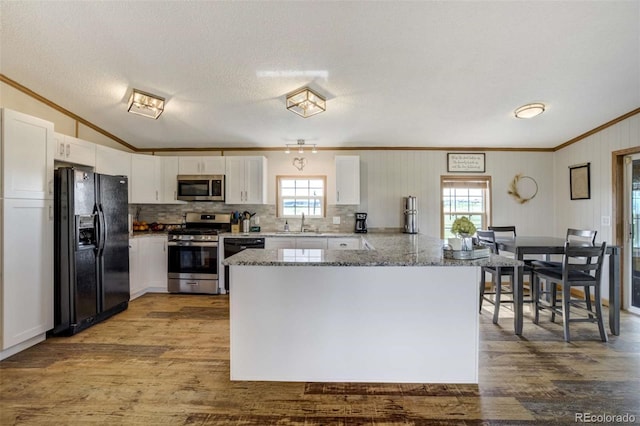 15650 W Valdez Cir, Peyton, CO 80831 - kitchen featuring appliances with stainless steel finishes, ornamental molding, a sink, wood finished floors, and white cabinetry