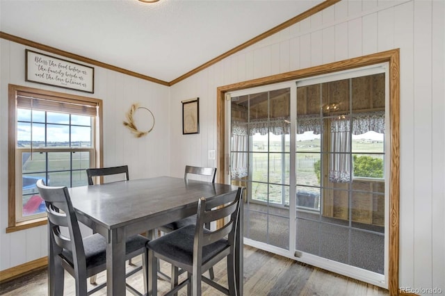 15650 W Valdez Cir, Peyton, CO 80831 - dining space featuring ornamental molding, wood finished floors, lofted ceiling, and wood walls