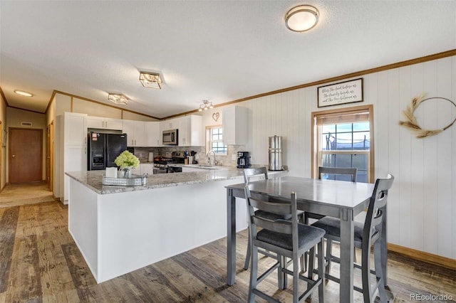 15650 W Valdez Cir, Peyton, CO 80831 - kitchen with appliances with stainless steel finishes, crown molding, wood finished floors, white cabinetry, and a sink