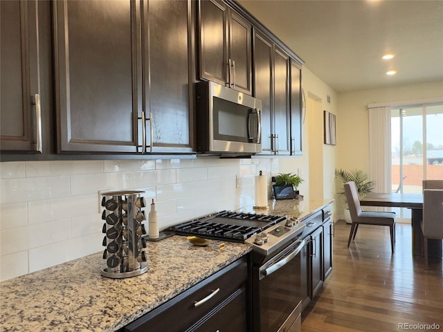 kitchen featuring light stone counters, dark brown cabinets, backsplash, and stainless steel appliances