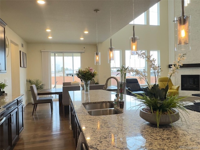 kitchen featuring sink, dark hardwood / wood-style flooring, pendant lighting, and light stone counters