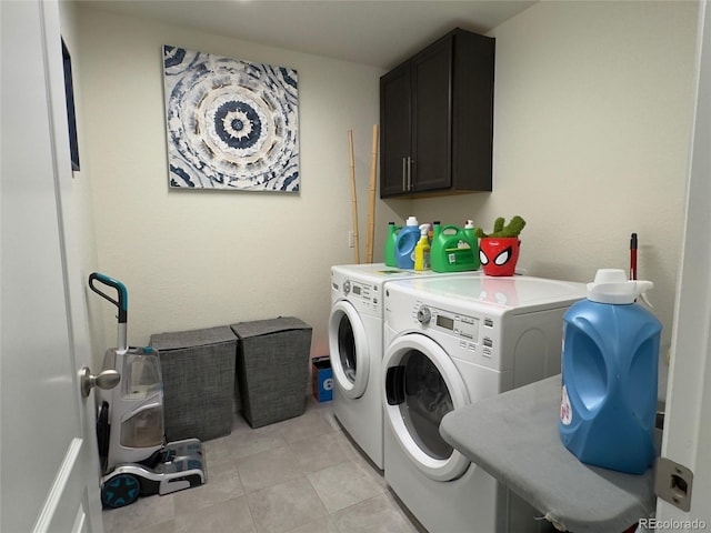 laundry room featuring washer and clothes dryer, light tile patterned floors, and cabinets