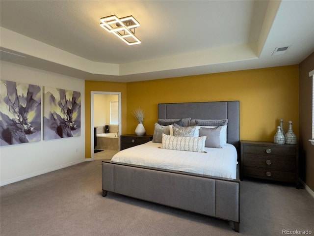 carpeted bedroom featuring connected bathroom and a raised ceiling