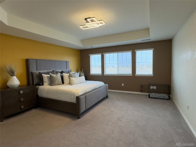 bedroom with light colored carpet and a raised ceiling