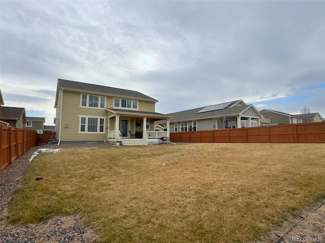 rear view of property featuring covered porch and a lawn