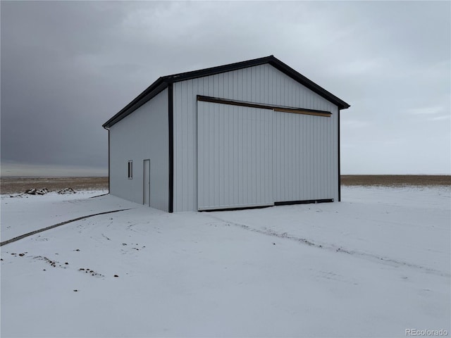 snow covered structure with a garage