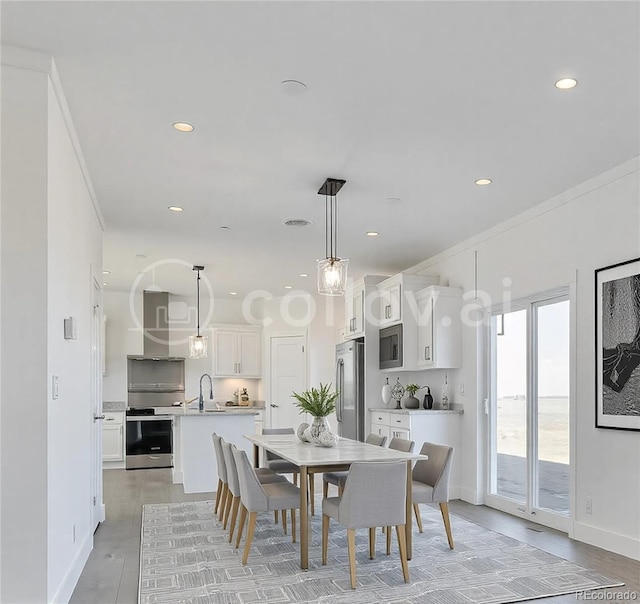 dining area with ornamental molding, sink, and light hardwood / wood-style flooring