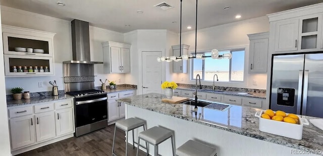 kitchen featuring white cabinetry, pendant lighting, appliances with stainless steel finishes, and wall chimney range hood