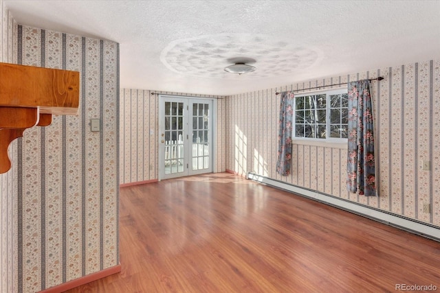 7032 County Road 156c, Salida, CO 81201 - empty room featuring wallpapered walls, wood finished floors, a textured ceiling, and a baseboard radiator