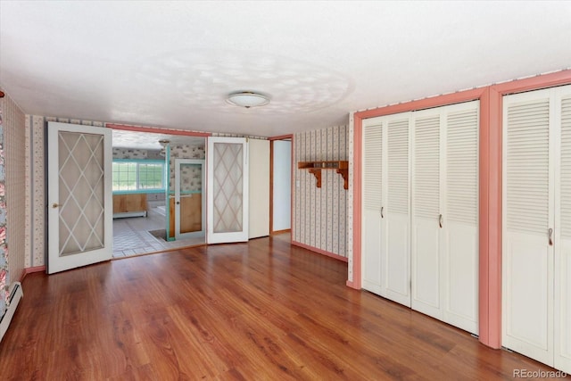 7032 County Road 156c, Salida, CO 81201 - unfurnished bedroom with multiple closets, baseboards, wood finished floors, and wallpapered walls