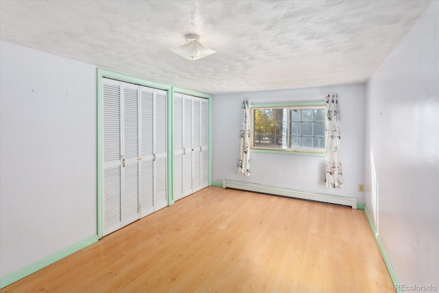 7032 County Road 156c, Salida, CO 81201 - unfurnished bedroom with baseboard heating, baseboards, wood finished floors, and two closets