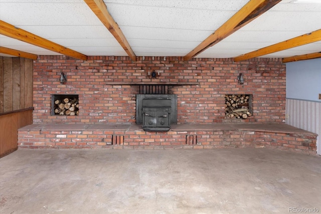 7032 County Road 156c, Salida, CO 81201 - unfurnished living room featuring wooden walls, beam ceiling, a wood stove, and unfinished concrete flooring