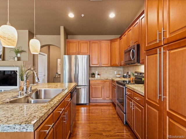 11962 W Long Cir Unit 203, Littleton, CO 80127 - kitchen with appliances with stainless steel finishes, arched walkways, wood finished floors, decorative light fixtures, and tasteful backsplash