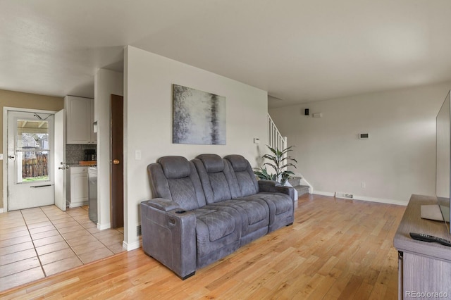 living area with baseboards, light wood finished floors, stairs, and visible vents
